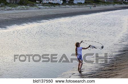 Stock Image - Caucasian girl fishing with net on beach. Fotosearch