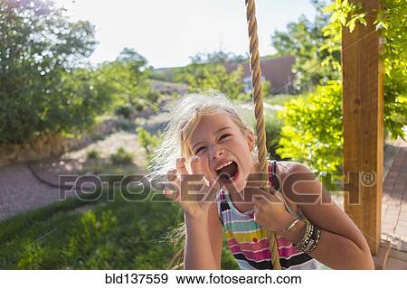 Stock Photo - Caucasian girl playing on rope swing. Fotosearch