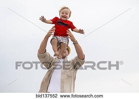 Stock Image - Caucasian man playing with grandson outdoors. Fotosearch