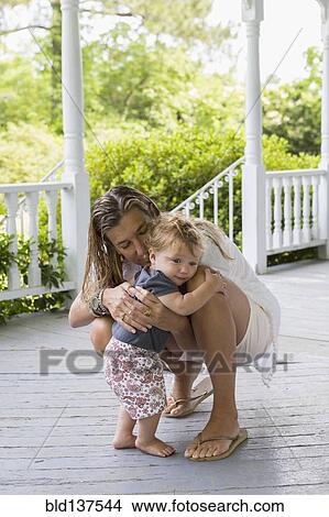 Picture - Caucasian mother hugging toddler on porch. Fotosearch