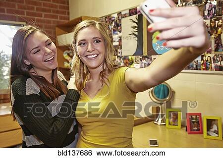 Stock Photograph - Caucasian students taking pictures in dorm room. Fotosearch