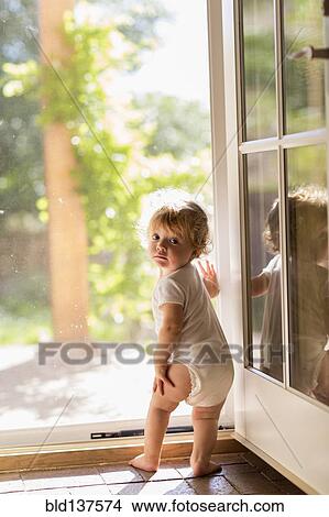 Picture - Caucasian toddler standing in doorway. Fotosearch