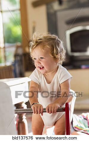 Stock Photograph - Caucasian toddler standing in living room. Fotosearch