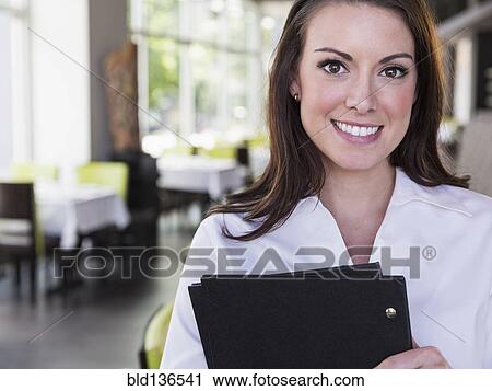 Stock Image - Caucasian waitress smiling in restaurant. Fotosearch