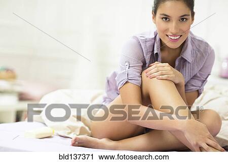 Stock Image - Caucasian woman smiling on bed. Fotosearch