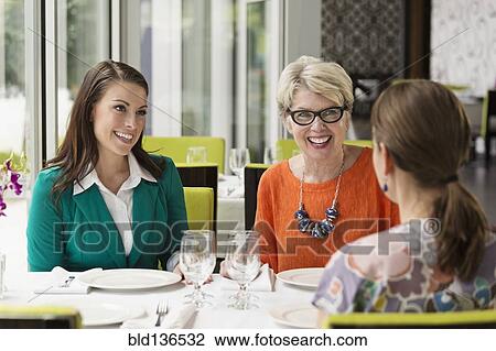 Stock Image - Caucasian women talking in restaurant. Fotosearch