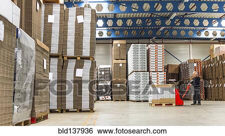 Stock Photograph - Caucasian worker pushing pallet on dolly in warehouse. Fotosearch