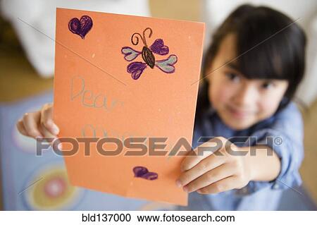 Stock Image - Close up of Filipino girl holding card for mother. Fotosearch