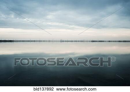 Stock Image - Clouds reflected in still rural lake. Fotosearch