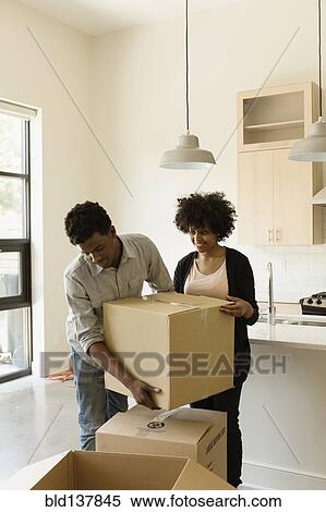 Couple hauling cardboard boxes in new house View Large Photo Image Stock Photography - Couple hauling cardboard boxes in new house. Fotosearch