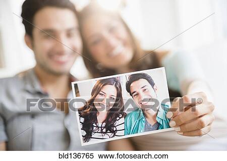 Stock Photography - Couple holding photograph of themselves. Fotosearch