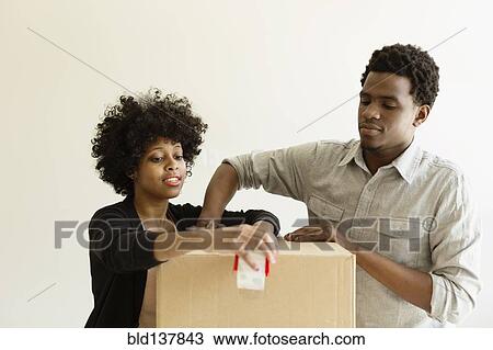 Stock Image - Couple packing cardboard box. Fotosearch