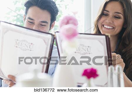Stock Image - Couple reading menus in restaurant. Fotosearch