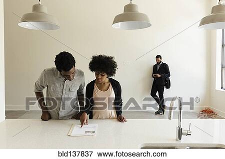 Stock Photo - Couple reading paperwork in new house. Fotosearch