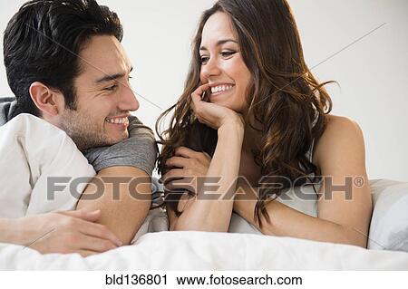 Couple relaxing together in bed View Large Photo Image Stock Image - Couple relaxing together in bed. Fotosearch