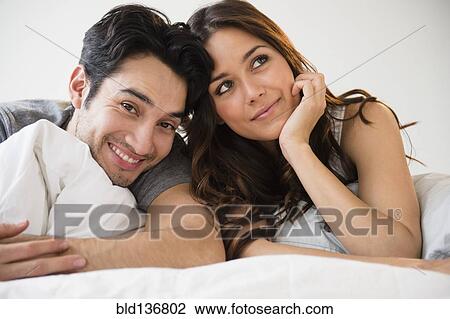 Couple relaxing together in bed View Large Photo Image Stock Image - Couple relaxing together in bed. Fotosearch