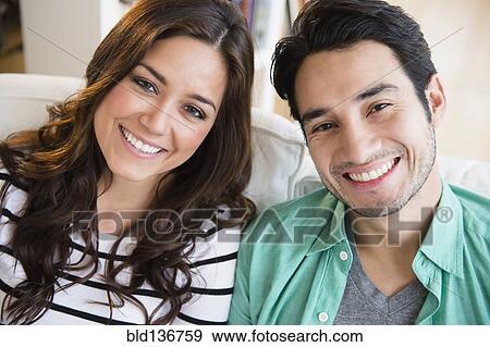 Stock Photo - Couple smiling together on sofa. Fotosearch
