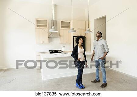 Stock Photography - Couple standing in kitchen in new house. Fotosearch