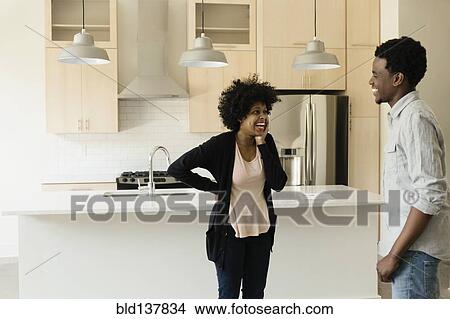 Picture - Couple talking in kitchen in new house. Fotosearch
