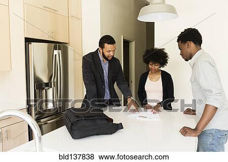 Stock Photo - Couple talking to broker in new house. Fotosearch