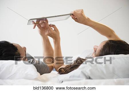 Couple using tablet computer in bed View Large Photo Image Stock Image - Couple using tablet computer in bed. Fotosearch