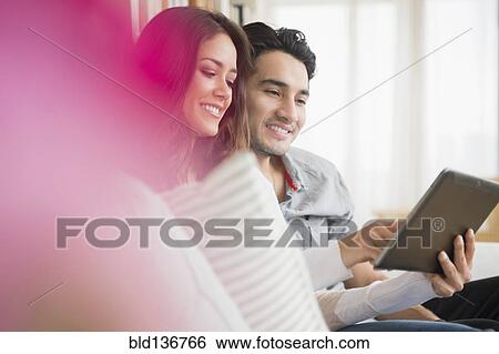 Stock Photograph - Couple using tablet computer on sofa. Fotosearch