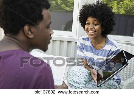 Stock Image - Couple using tablet computer together on porch. Fotosearch