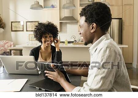 Picture - Couple using technology at breakfast table. Fotosearch