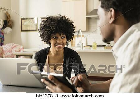 Stock Image - Couple using technology at breakfast table. Fotosearch