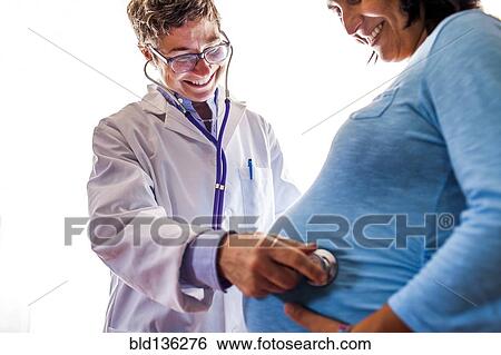 Stock Photograph - Doctor listening to woman's pregnant belly. Fotosearch