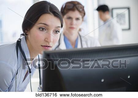 Stock Photograph - Doctors using computer in office. Fotosearch