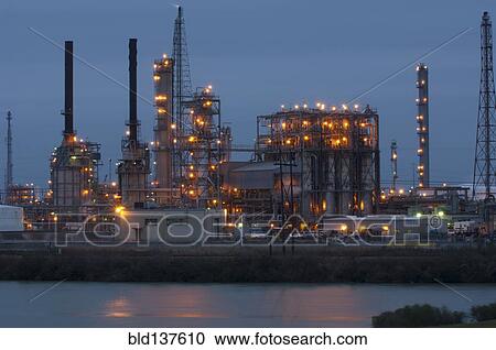 Stock Image - Factory near lake illuminated at night. Fotosearch