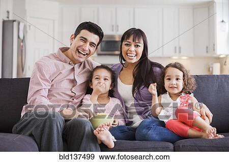 Stock Photo - Family smiling together on sofa. Fotosearch