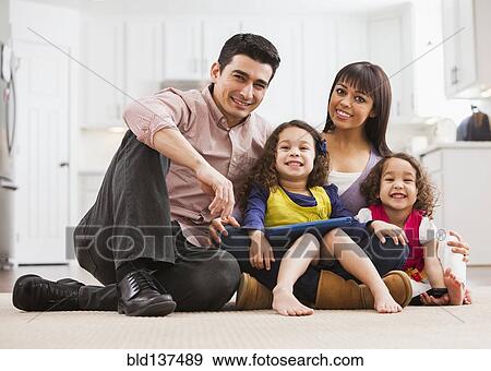 Stock Photo - Family using tablet computer on living room floor. Fotosearch