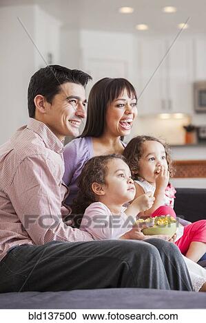 Stock Image - Family watching television together on sofa. Fotosearch