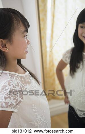 Stock Image - Filipino girl admiring herself in mirror. Fotosearch