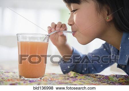 Stock Photo - Filipino girl drinking juice on table. Fotosearch