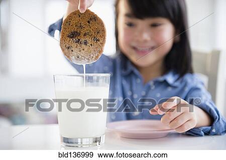 Filipino girl dunking cookie in milk View Large Photo Image Stock Photo - Filipino girl dunking cookie in milk. Fotosearch