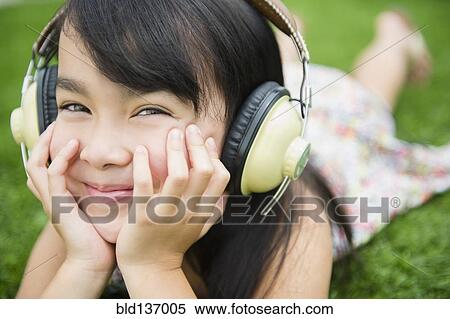Stock Photography - Filipino girl listening to headphones outdoors. Fotosearch