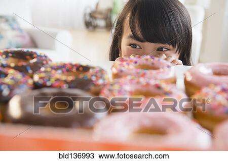 Filipino girl peering at donuts on table View Large Photo Image Stock Image - Filipino girl peering at donuts on table. Fotosearch