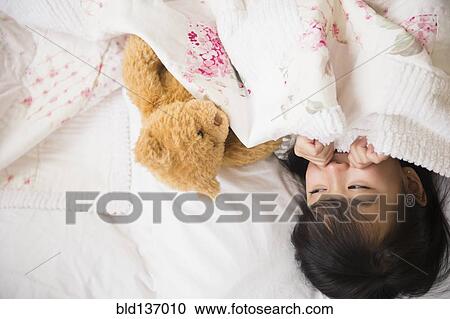 Filipino girl playing with teddy bear in bed View Large Photo Image Stock Image - Filipino girl playing with teddy bear in bed. Fotosearch
