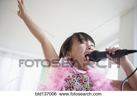 Filipino girl singing karaoke in living room View Large Photo Image Stock Photograph - Filipino girl singing karaoke in living room. Fotosearch