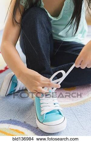 Filipino girl tying her shoelaces View Large Photo Image Picture - Filipino girl tying her shoelaces. Fotosearch