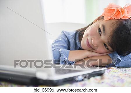 Stock Photography - Filipino girl using laptop at desk. Fotosearch