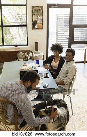 Stock Photograph - Friends relaxing together at table. Fotosearch
