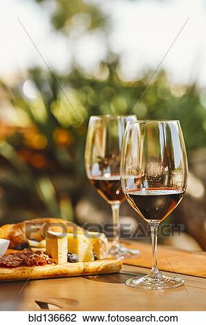 Stock Image - Glasses of wine with cheese and meat board. Fotosearch