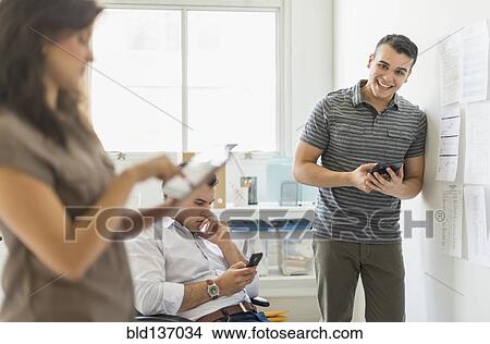 Picture - Hispanic business people using technology in office. Fotosearch