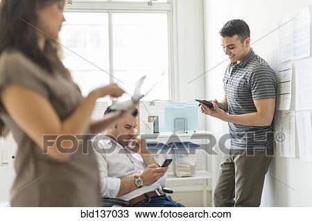 Stock Image - Hispanic business people using technology in office. Fotosearch