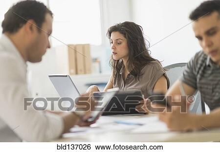 Stock Photograph - Hispanic business people using technology in office. Fotosearch