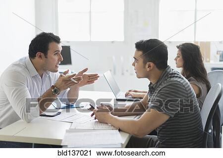 Stock Image - Hispanic business people working together in office. Fotosearch